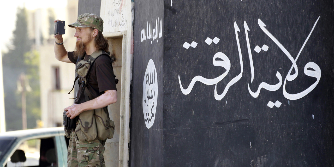 A militant Islamist fighter uses a mobile to film his fellow fighters taking part in a military parade along the streets of Syria's northern Raqqa province June 30, 2014. The fighters held the parade to celebrate their declaration of an Islamic "caliphate" after the group captured territory in neighbouring Iraq, a monitoring service said. The Islamic State, an al Qaeda offshoot previously known as Islamic State in Iraq and the Levant (ISIL), posted pictures online on Sunday of people waving black flags from cars and holding guns in the air, the SITE monitoring service said. Picture taken June 30, 2014.  REUTERS/Stringer (SYRIA - Tags: POLITICS CIVIL UNREST CONFLICT) - RTR3WKOJ